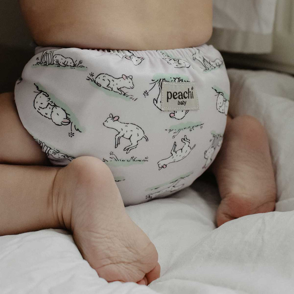 baby wearing a lilac lamb print cloth nappy