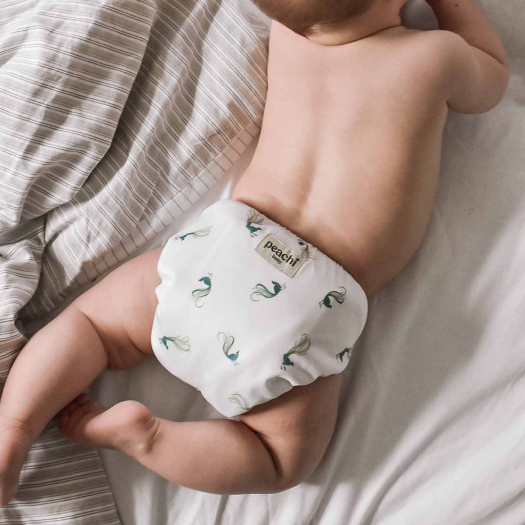 Baby wearing a modern cloth nappy in a lyrebird print