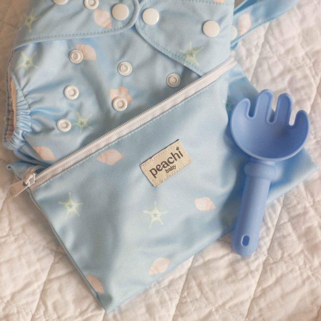 Peachi Baby Reusable Nappy Wet Bag in a Blue Seashells Print with a seashells cloth nappy