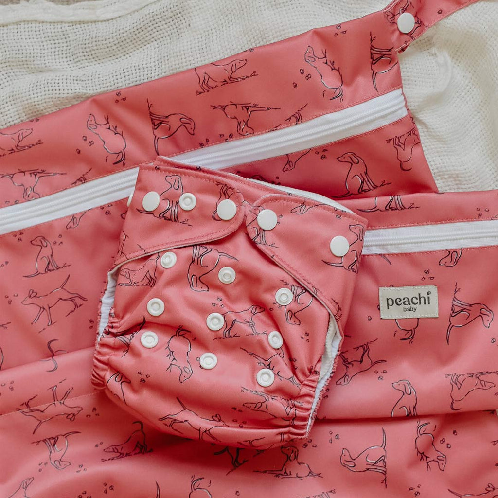 wetbag for baby's dirty items in a red dogs print. pictured with a matching cloth nappy