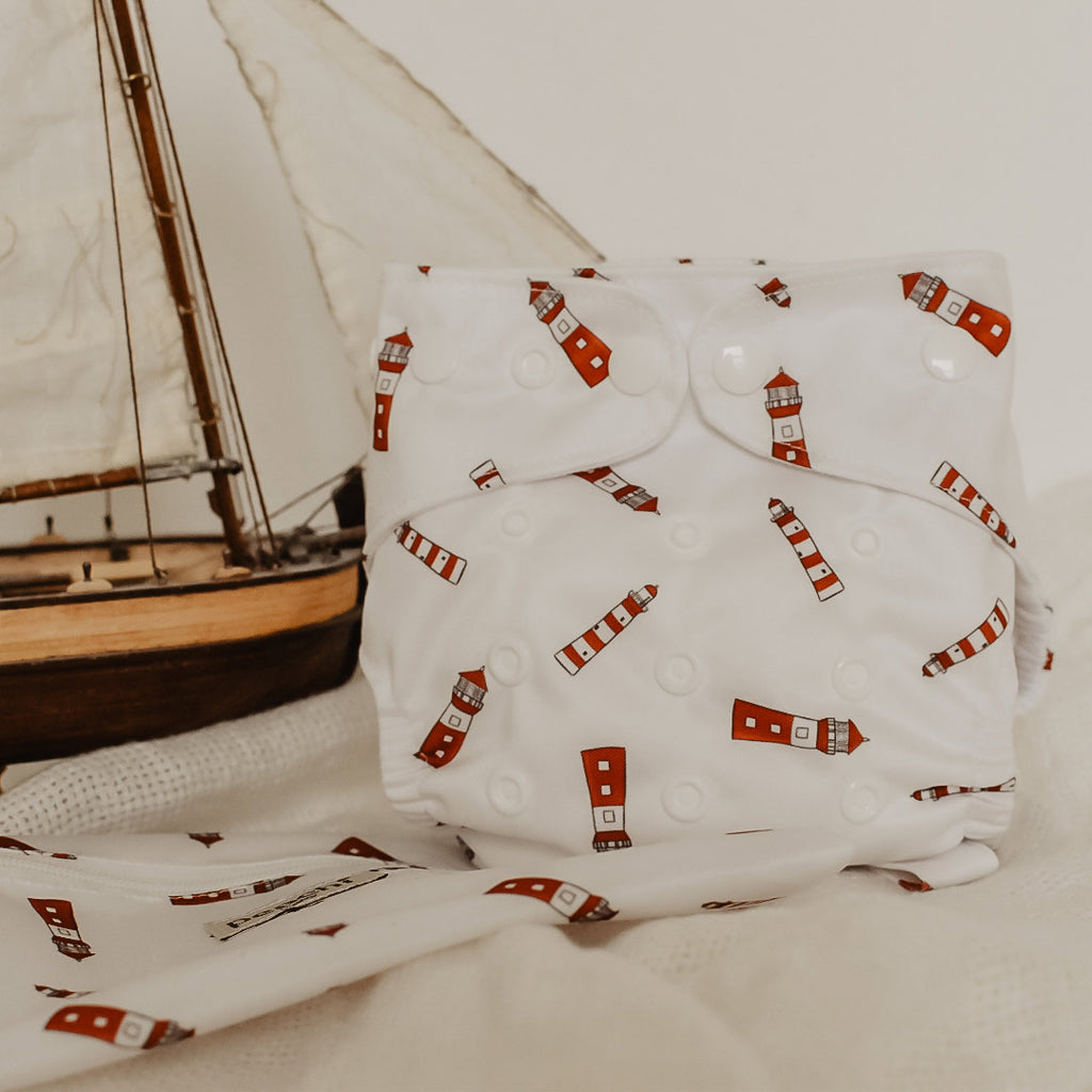 a lighthouse print modern cloth nappy pictured with a boat