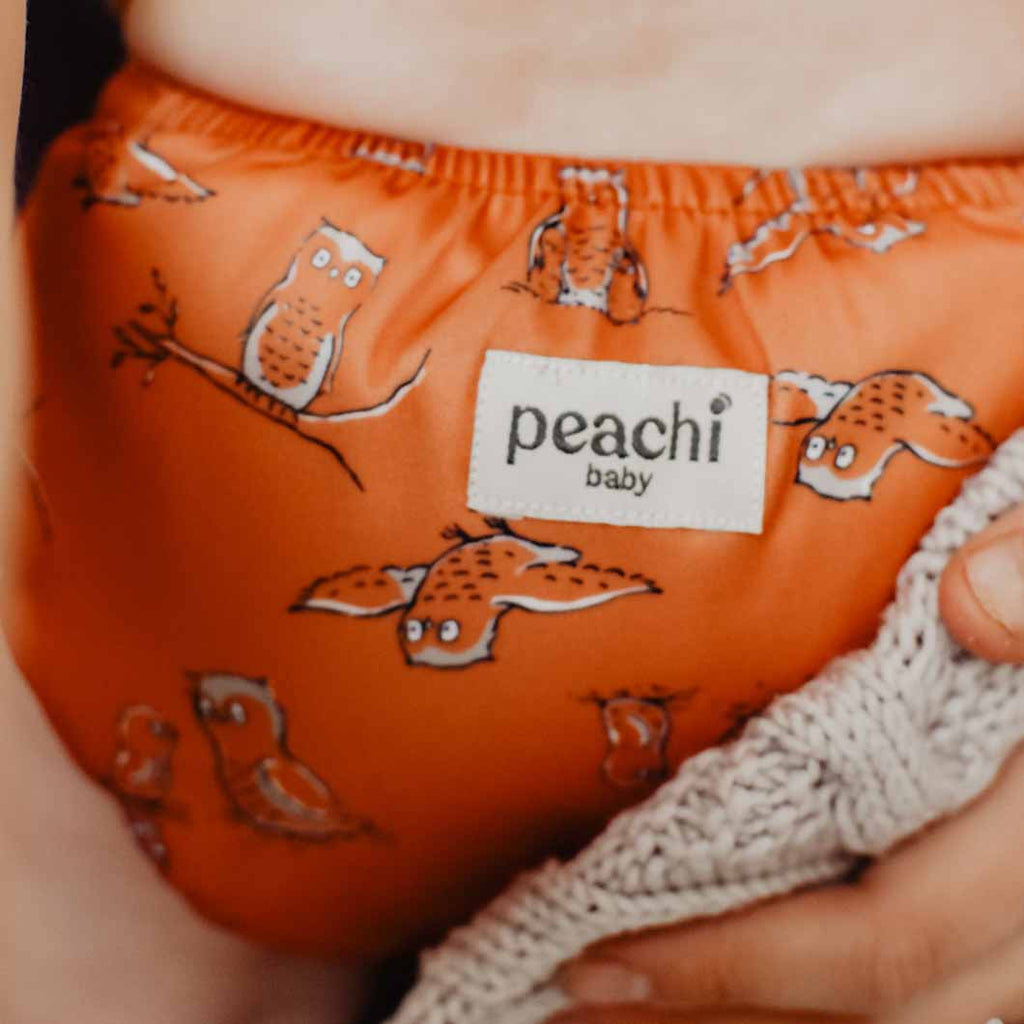 child wearing an orange owls print reusable modern cloth nappy by peachi baby